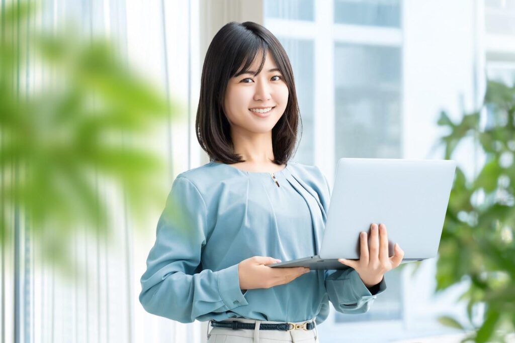 パソコンを持ってこちらを見る青い服の女性