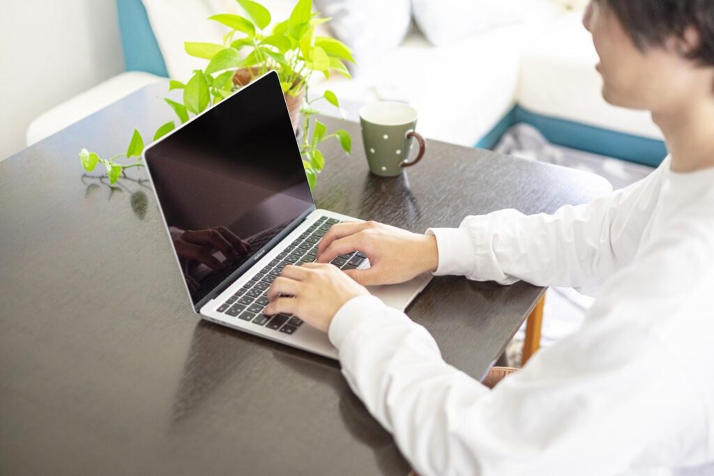 自宅のテーブルの上でタイピングしている人の手元