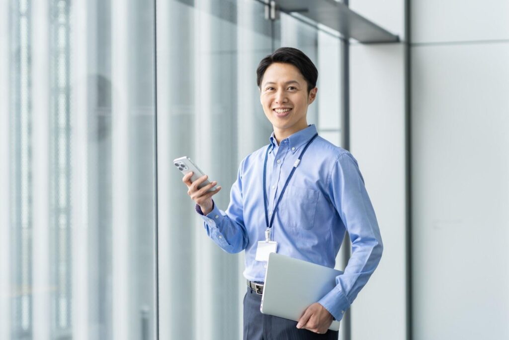 スマートフォンを持ってこちらに微笑む青スーツの男性