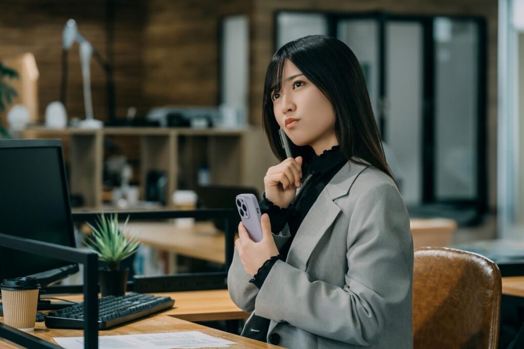 FXはなぜ9割が負けると言われるのかについて考えているオフィスカジュアル服の女性