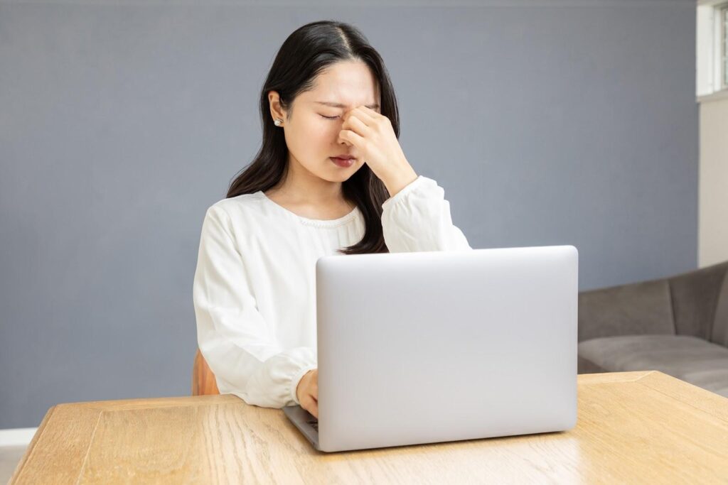目頭を指でつまみながら悩んでいる白服の女性