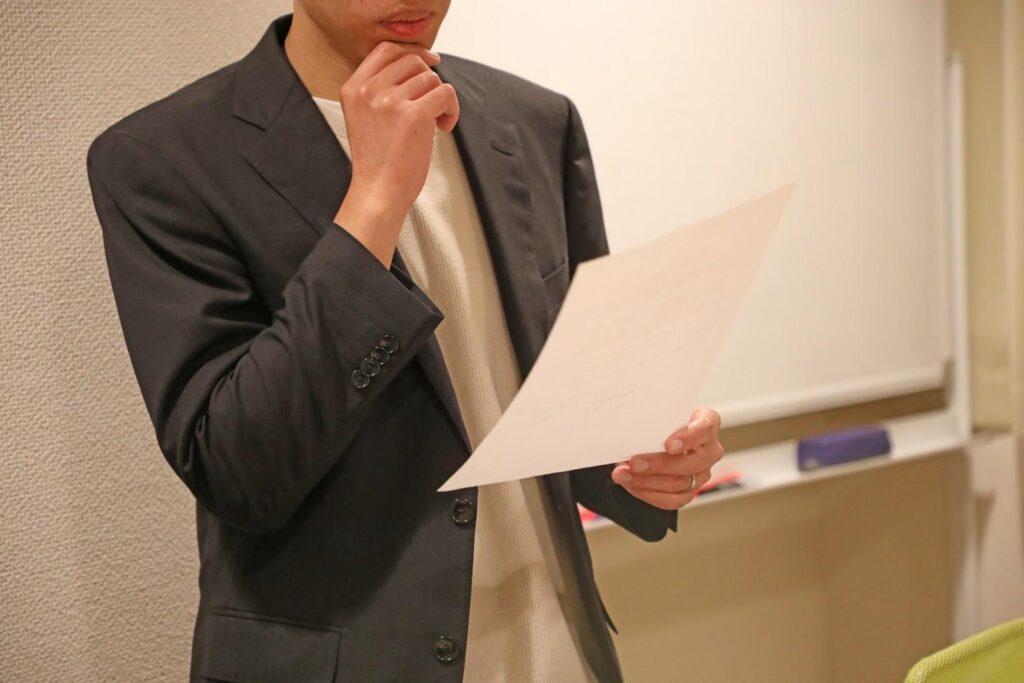 FX資金管理の基本ルールについて書類を見ながら考えるオフィスカジュアル服の男性