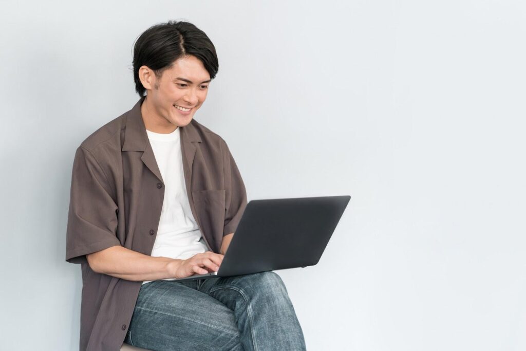 にこやかに座りながらパソコン作業する男性
