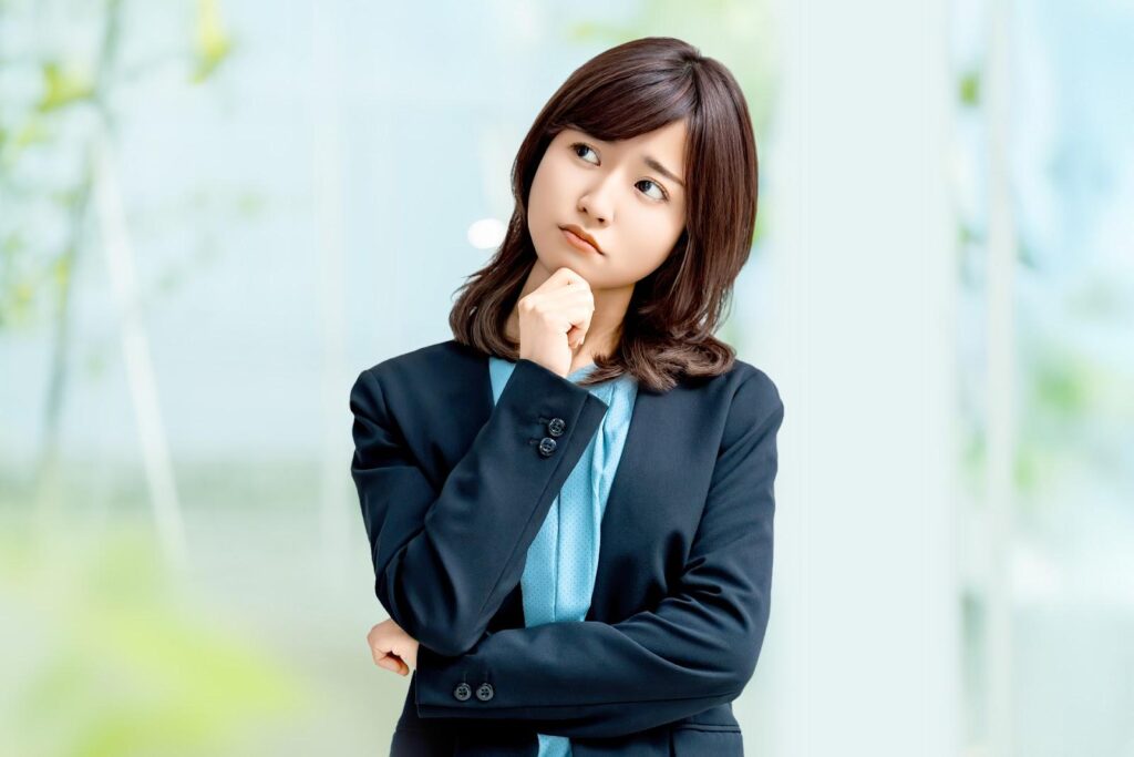 腕を組んで悩むスーツ姿の女性