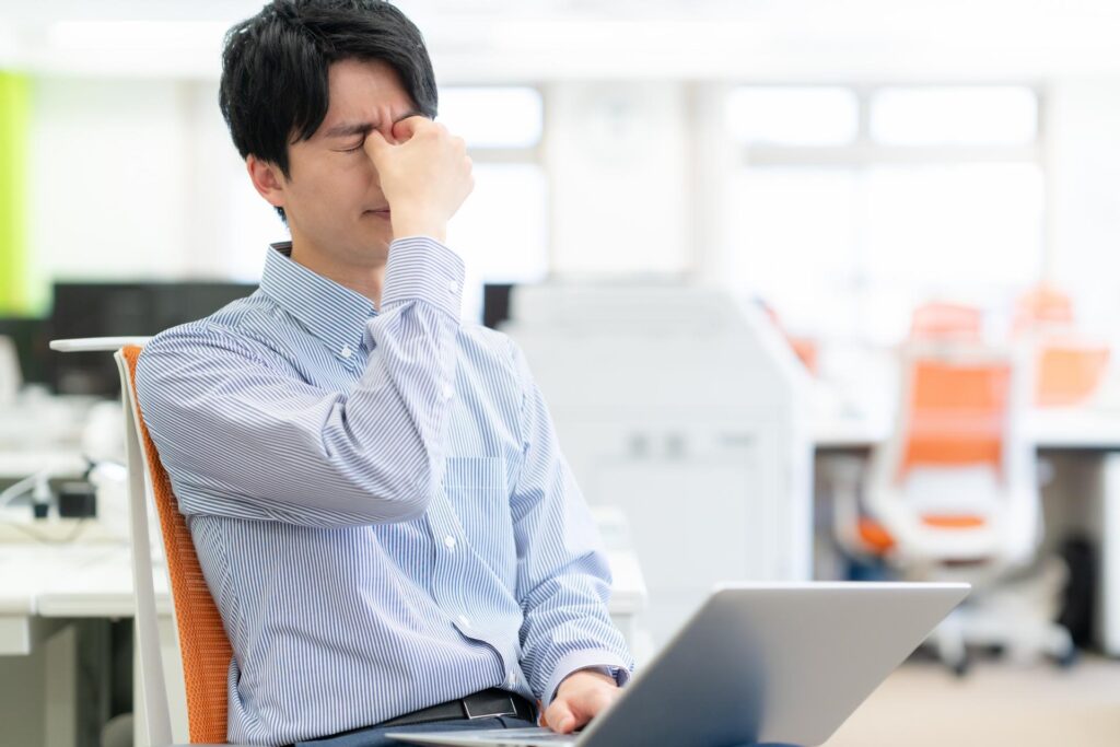 眉間を指でつかみながら悩む青スーツの男性