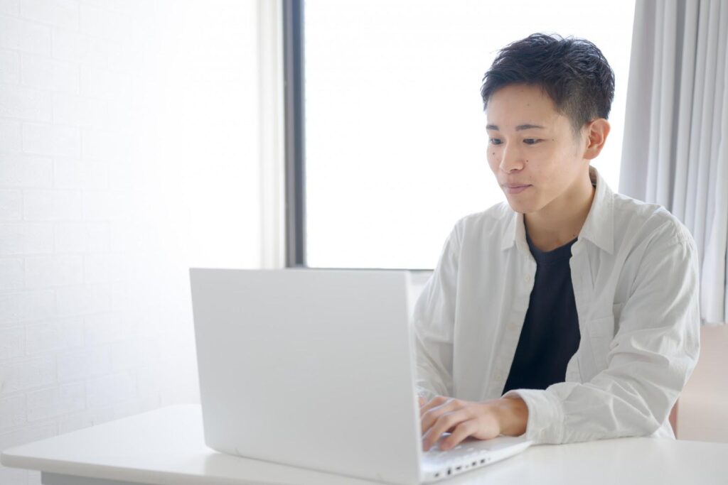 自宅でパソコン作業をする白服の男性