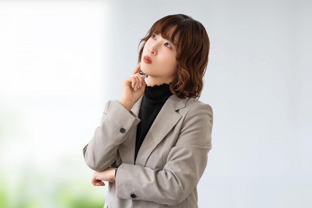 8つの売買サインについて考えるオフィスカジュアル服の女性