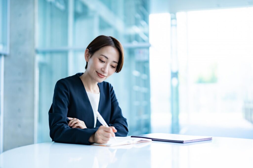 FXの両建てについてペンを持って勉強しているオフィスカジュアルの女性
