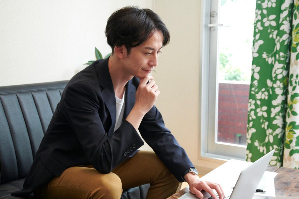 FXのスリッページの仕組みについて自宅のパソコンで調べながら考える男性