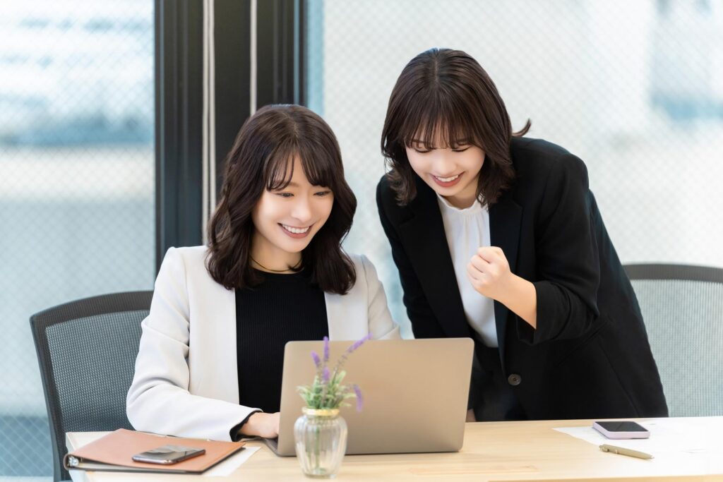 パソコンでFX取引をしている2人の女性