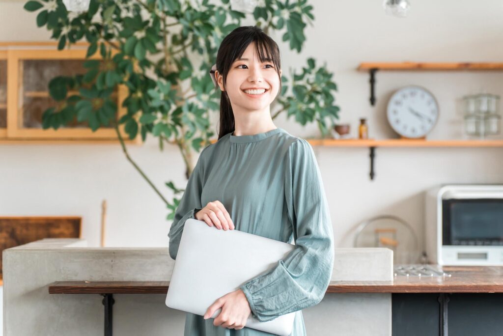 パソコンを脇に抱えて楽しそうに遠くを見つめる女性