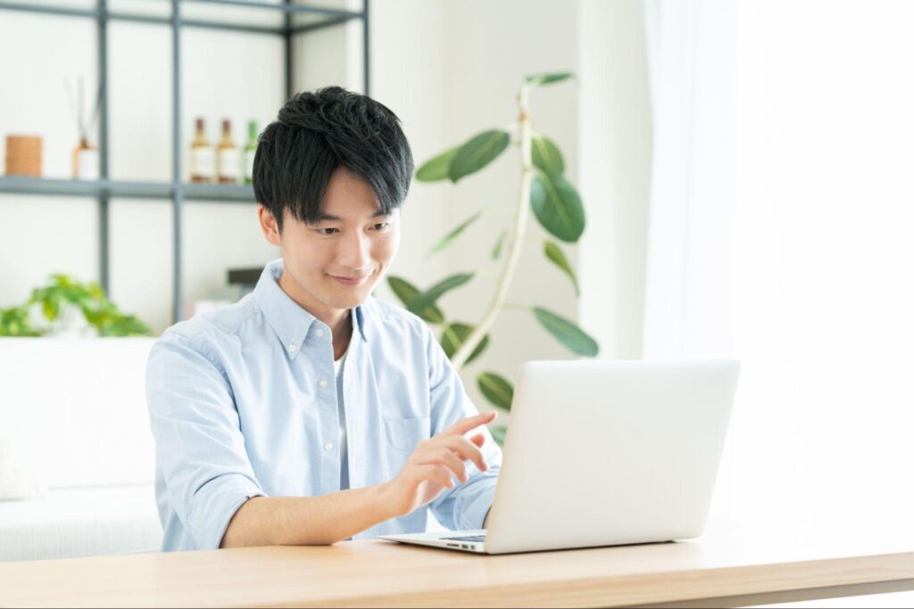自宅のPCでFXの戦略を立てながら満足そうな表情を浮かべる男性