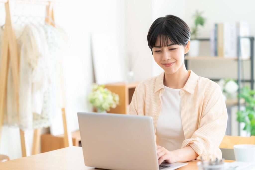 自宅でパソコンを開いて週明けのFX取引をしている私服の女性