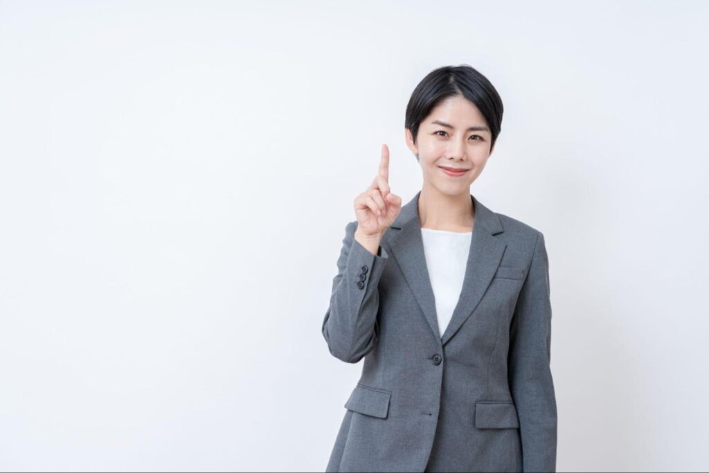 人差し指を立てて解説しているオフィスカジュアルの女性