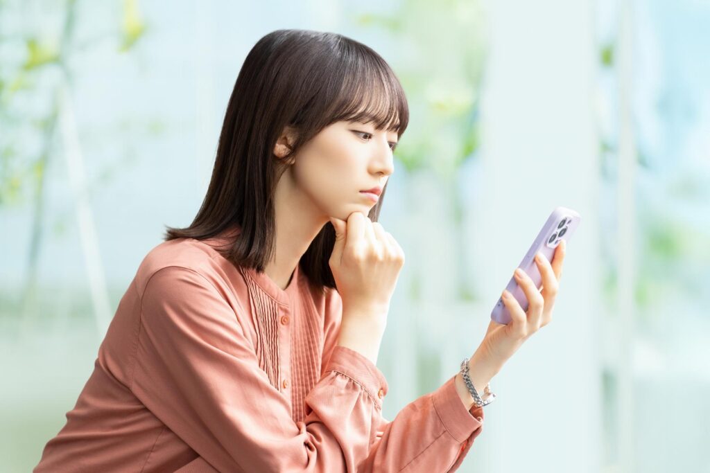 スマホでFX取引のデメリットを確認する女性