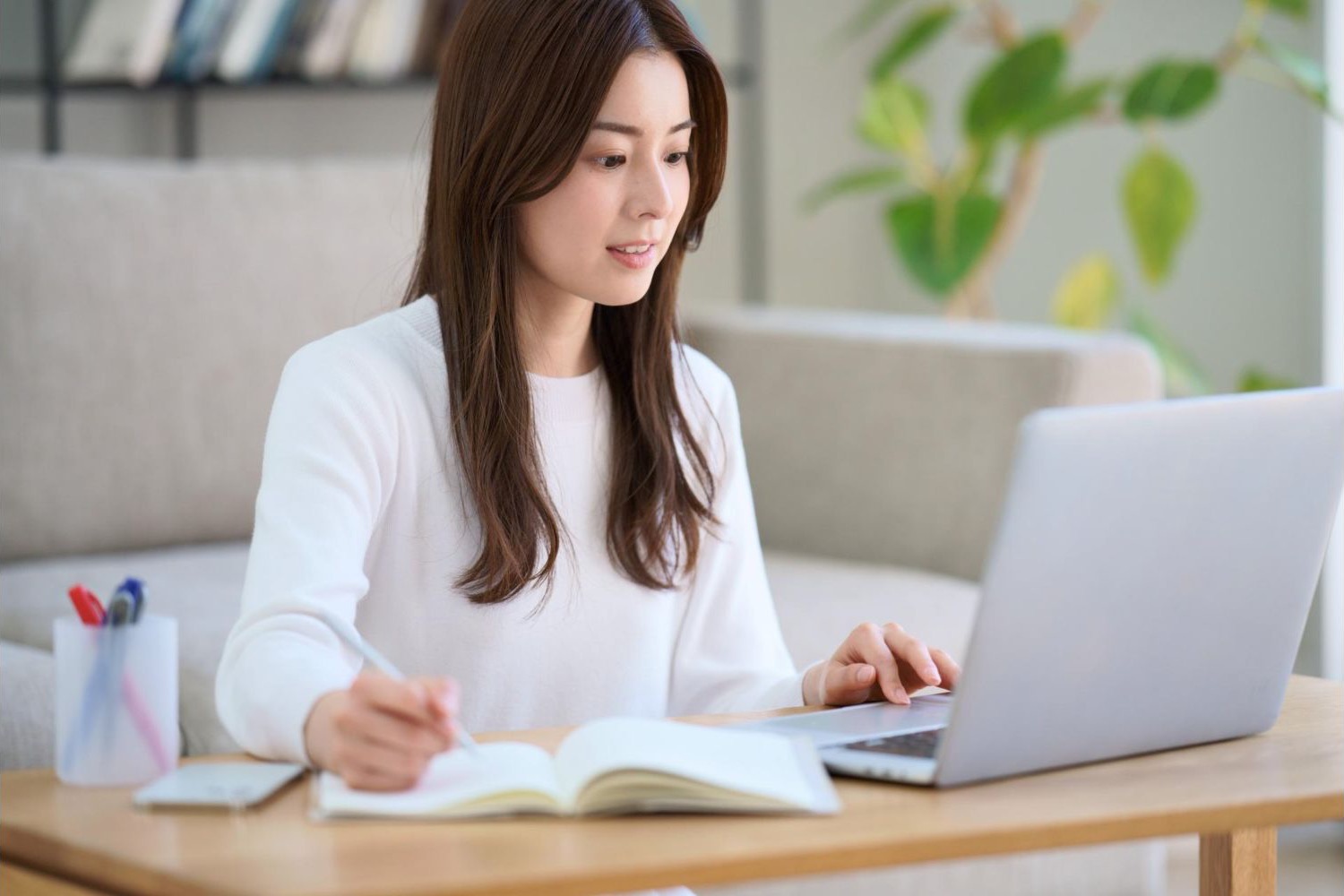 ノートを開き、ノートパソコンで学習する女性