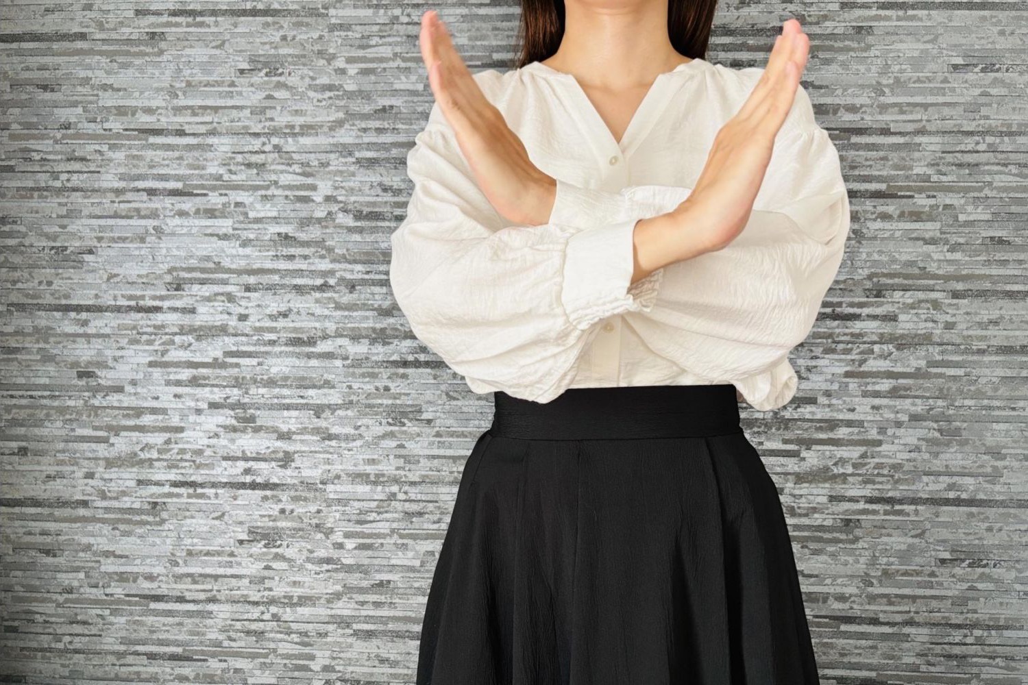 胸の前で両腕を交差し、禁止の意思を示す女性