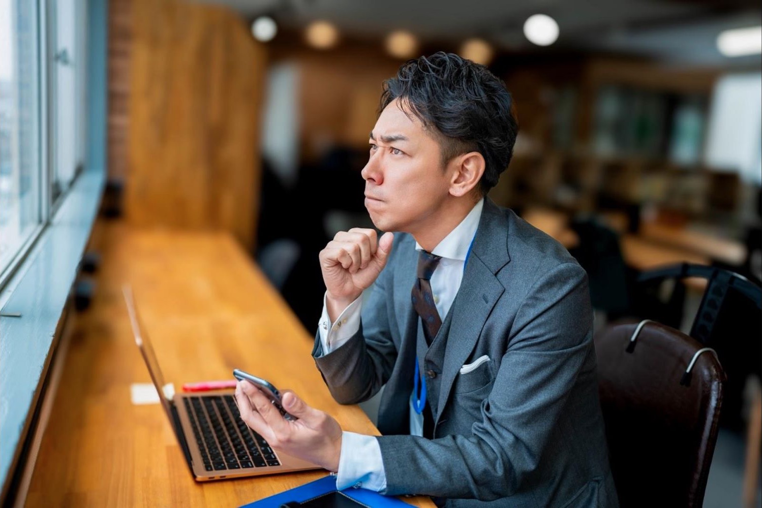カフェでタブレットを見ながら考える男性会社員