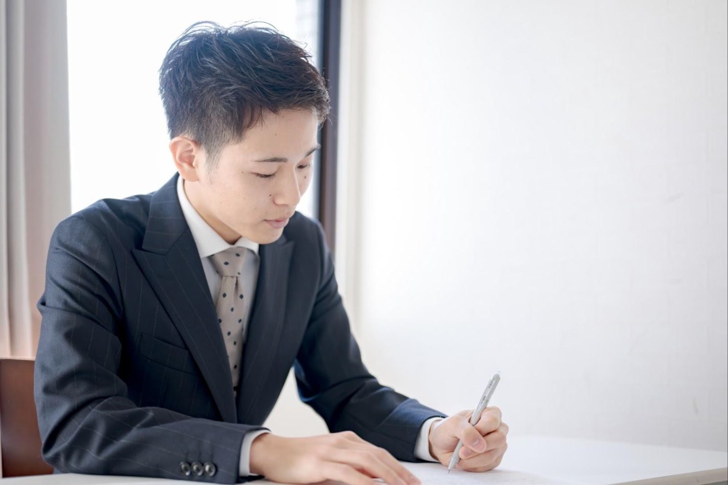 机の書類にペンで記入する男性会社員