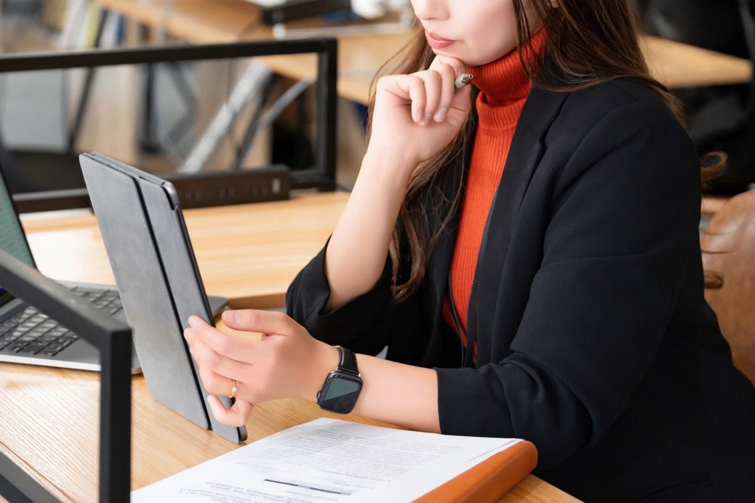 カフェでタブレットを見ながら考える女性