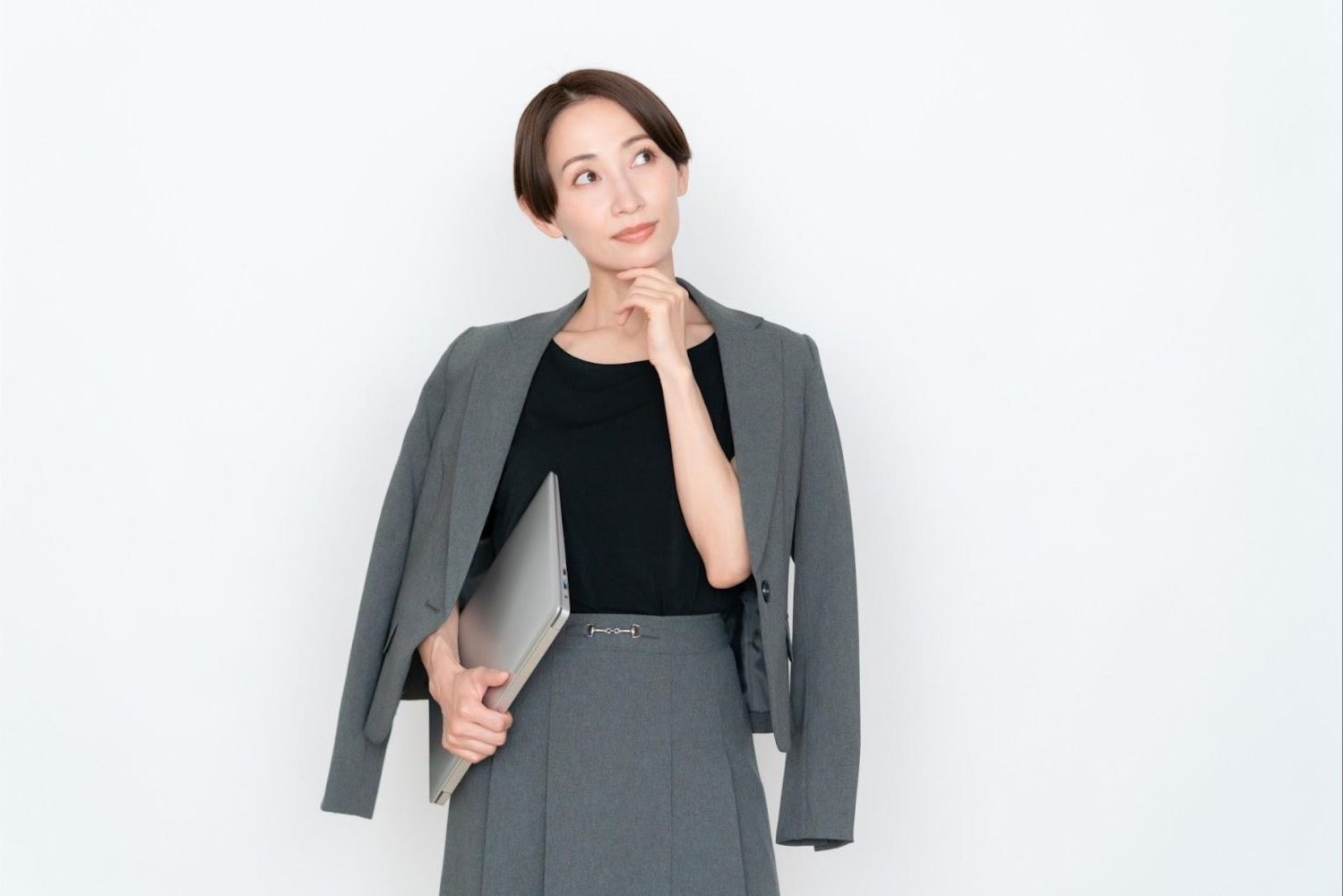 ファイルを抱え、顎に手を当てて考える女性会社員
