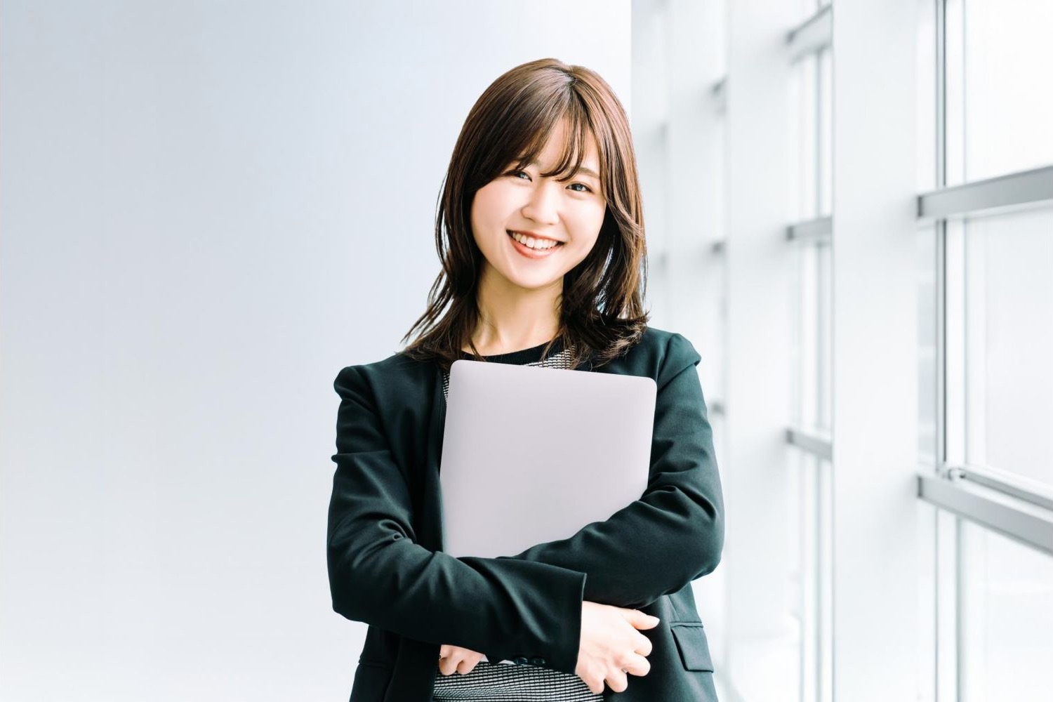 書類を抱えて笑顔で立つ女性会社員