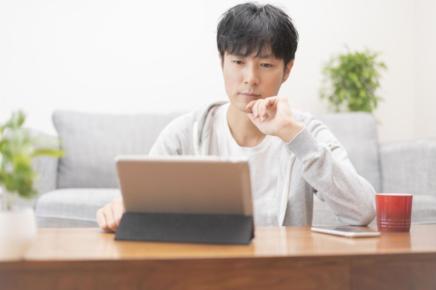 タブレットの画面を見ながら考える男性
