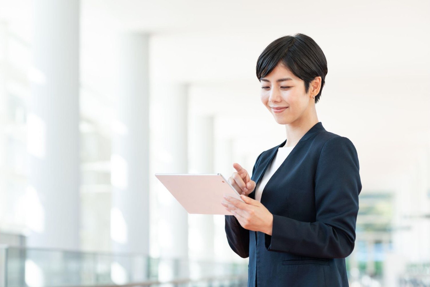 タブレットを操作しながら立つ女性会社員