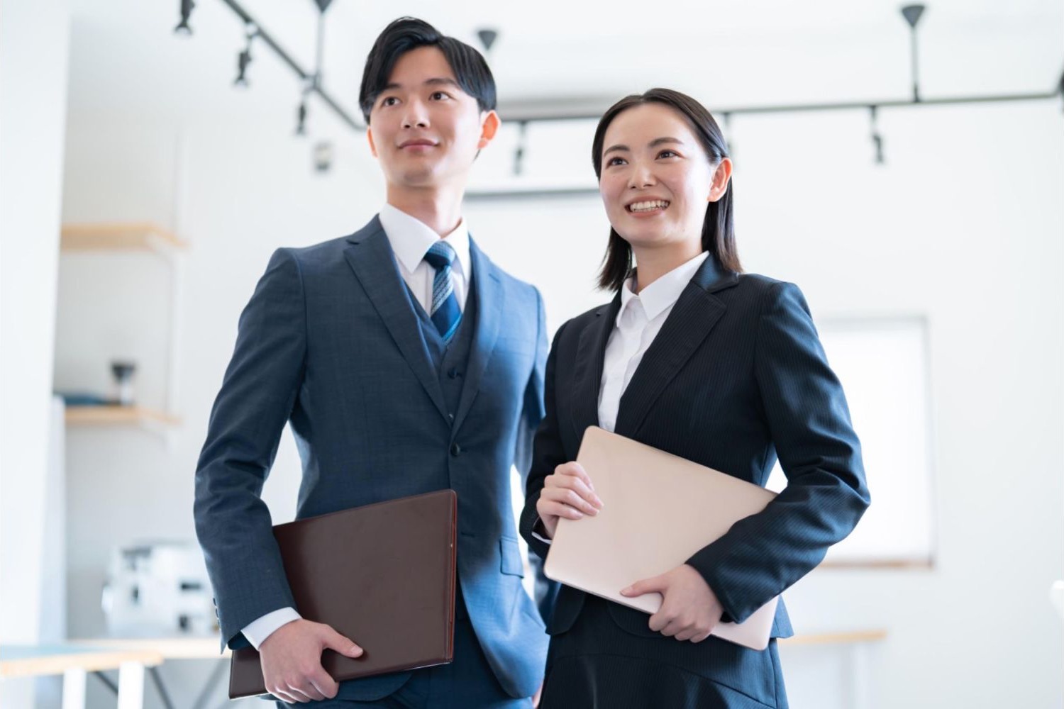 ファイルを持ち、並んで立つ男女の会社員
