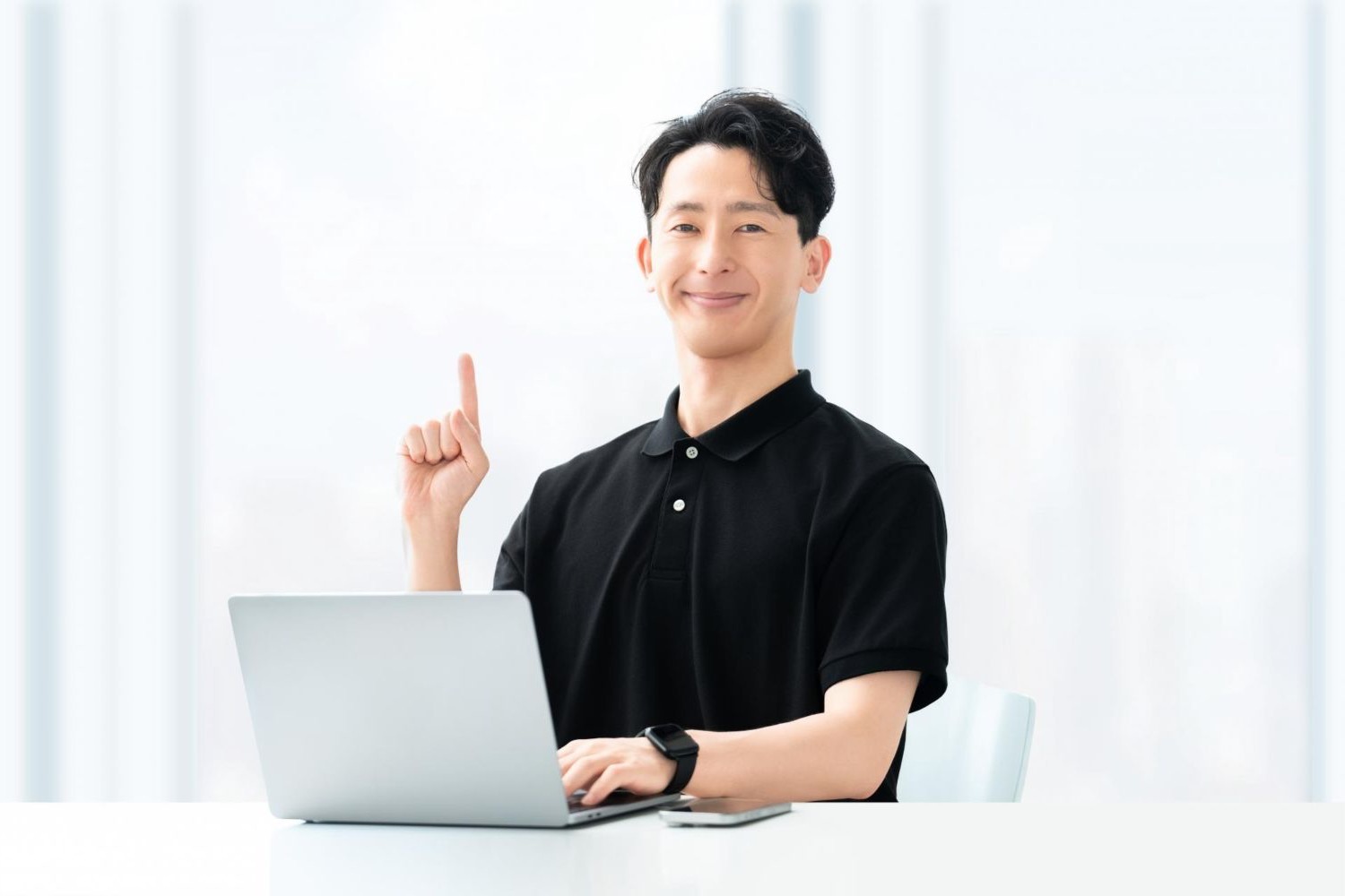 ノートパソコンの前で人差し指を立てる男性
