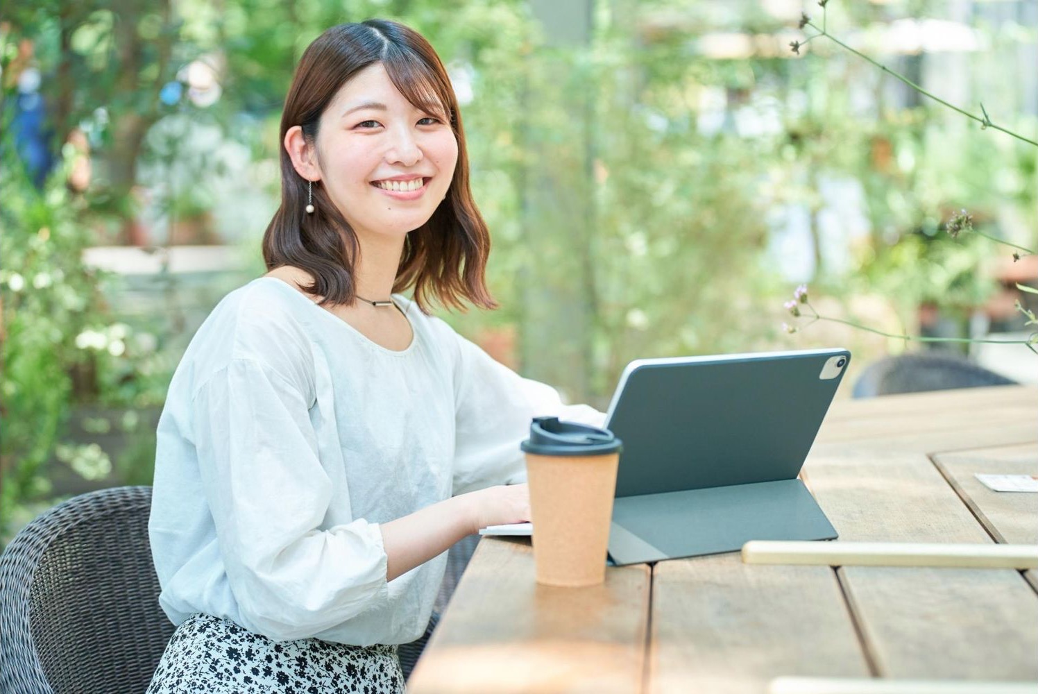 屋外のテーブルでタブレットを操作する女性