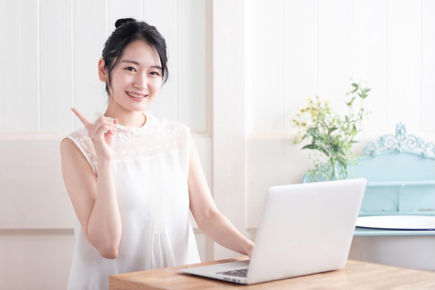 明るい部屋でノートパソコンを開き、手で合図する女性