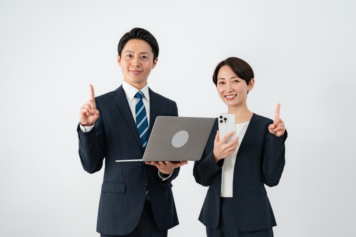 ノートパソコンを持ち、人差し指を立てる男女の会社員