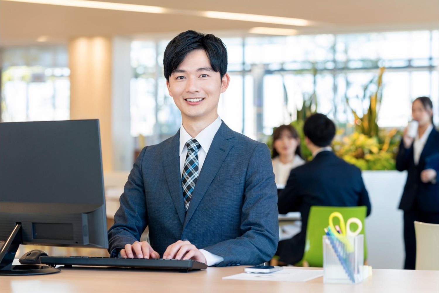 オフィスのデスクで笑顔を見せる男性会社員