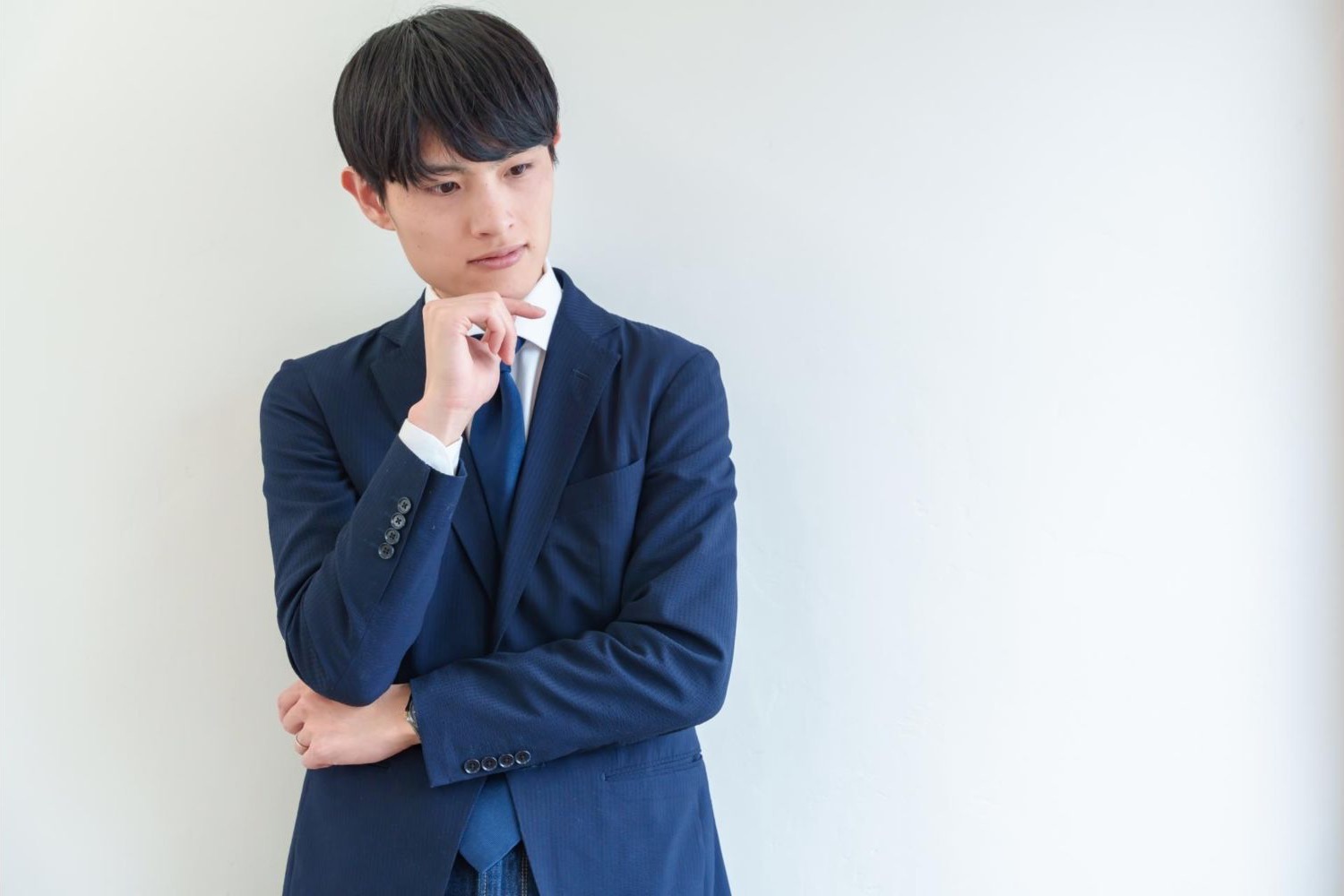 腕を組み、顎に手を当てて考える男性会社員