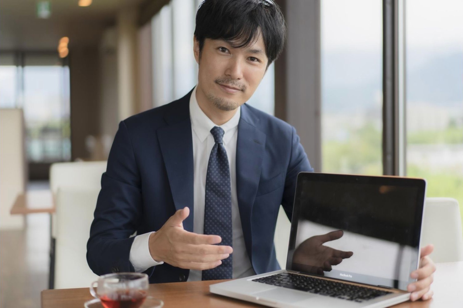 ノートパソコンの画面を示しながら説明する男性