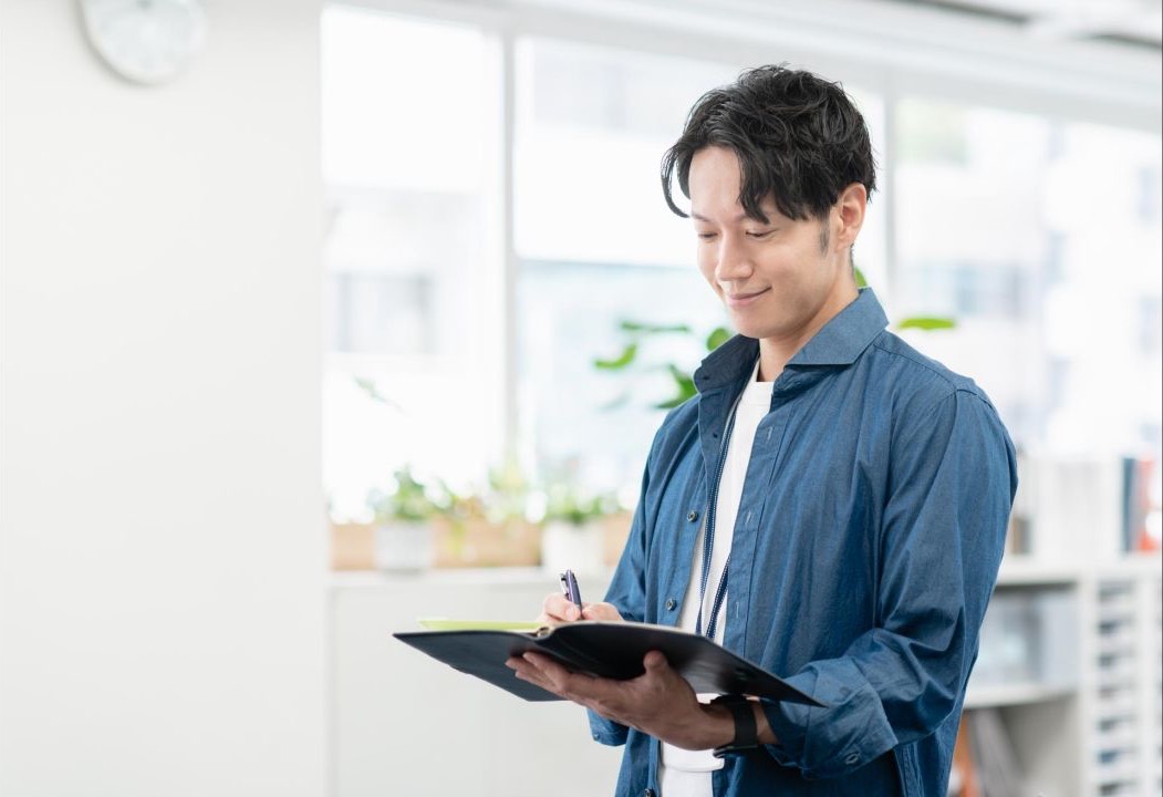 タブレットにメモを取りながらオフィスに立つ男性