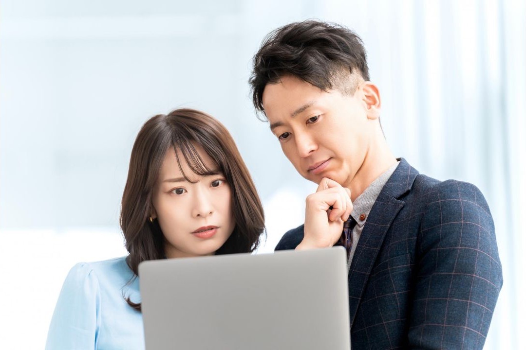 ノートパソコンの画面を一緒に見ながら考える男女