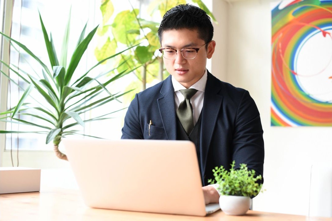 オフィスの机でノートパソコンを操作する男性会社員