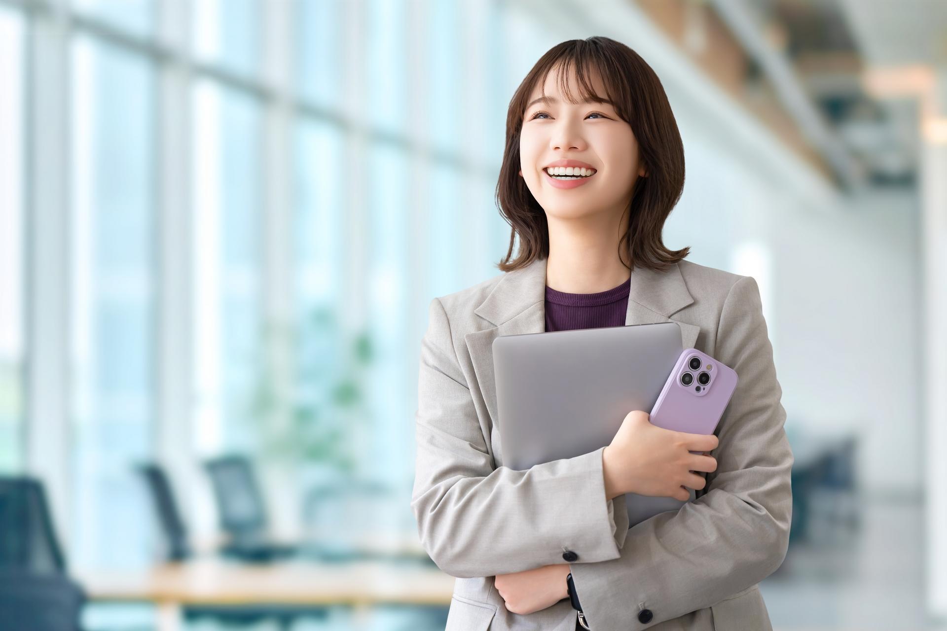 パソコンとスマホを持つ笑顔の女性