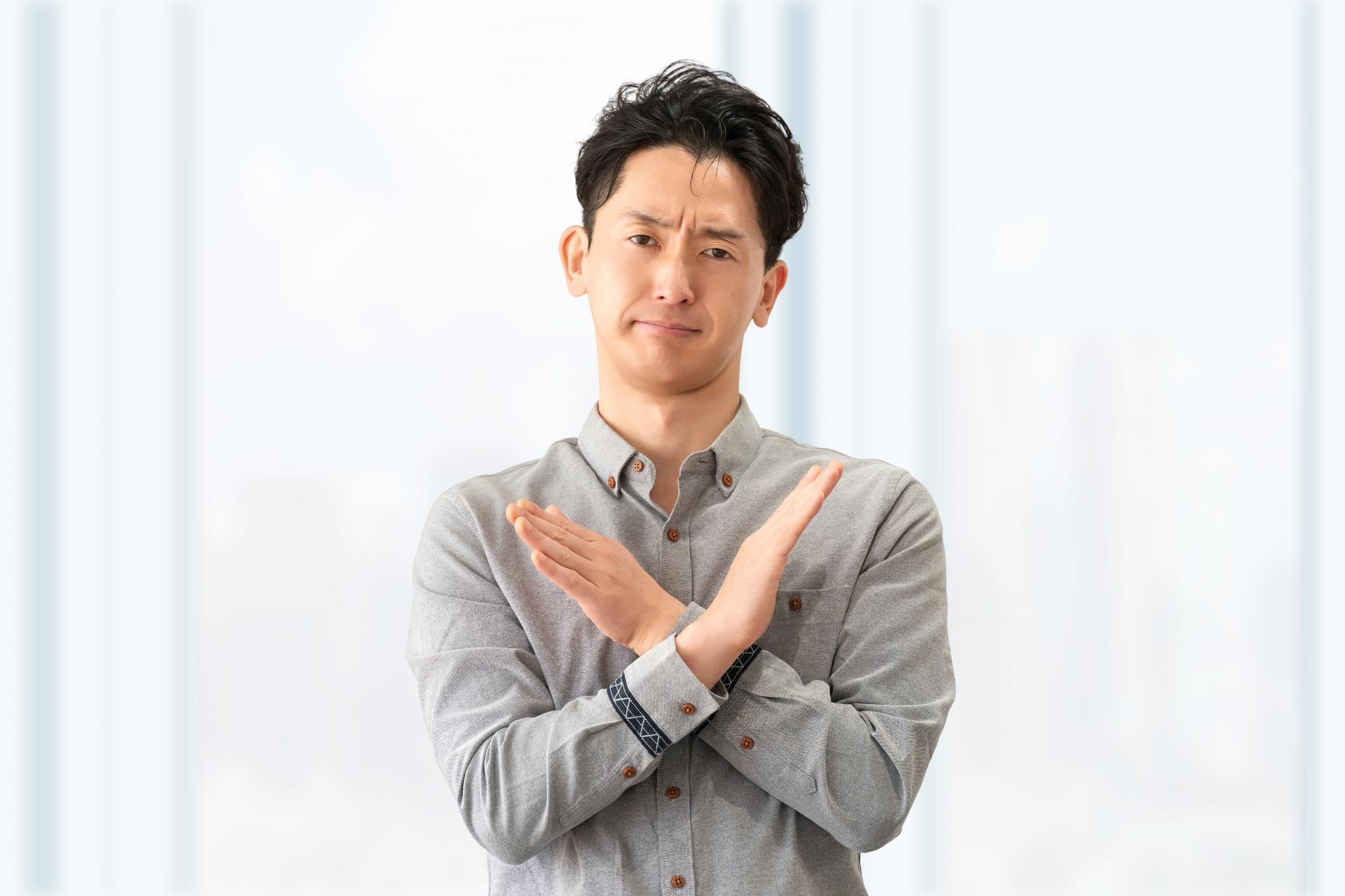 手でバツのポーズをする男性ビジネスマン