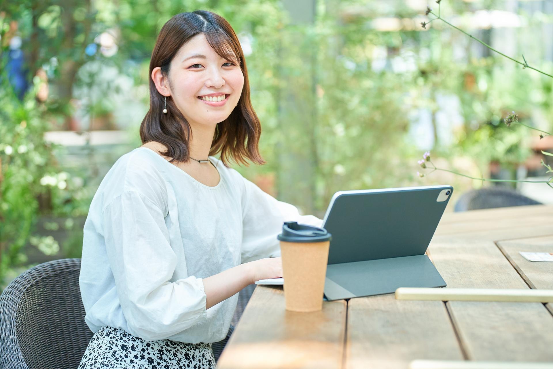 街角でタブレットPC操作をする笑顔の女性