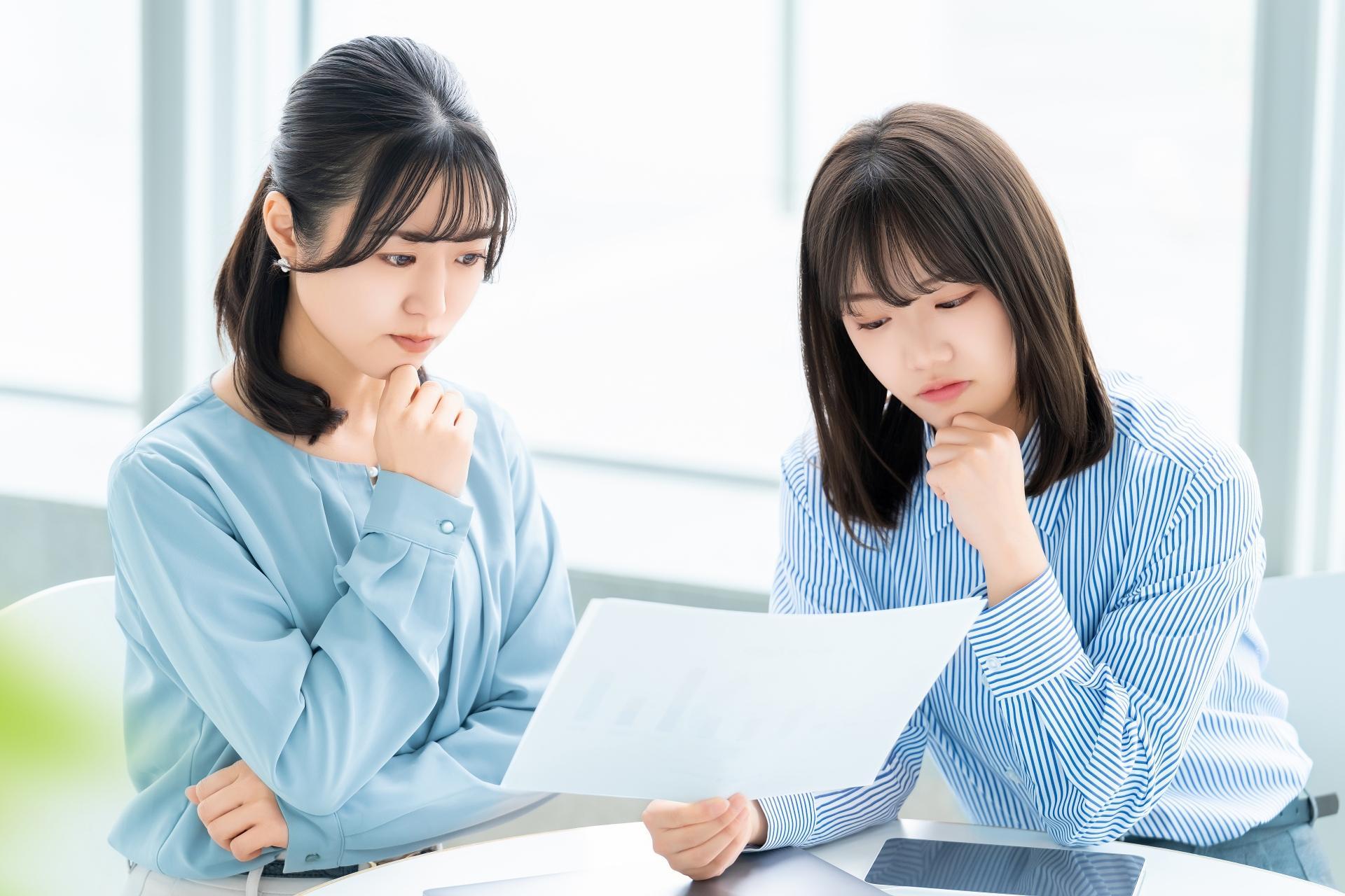 資料を見ながら考える2人の女性