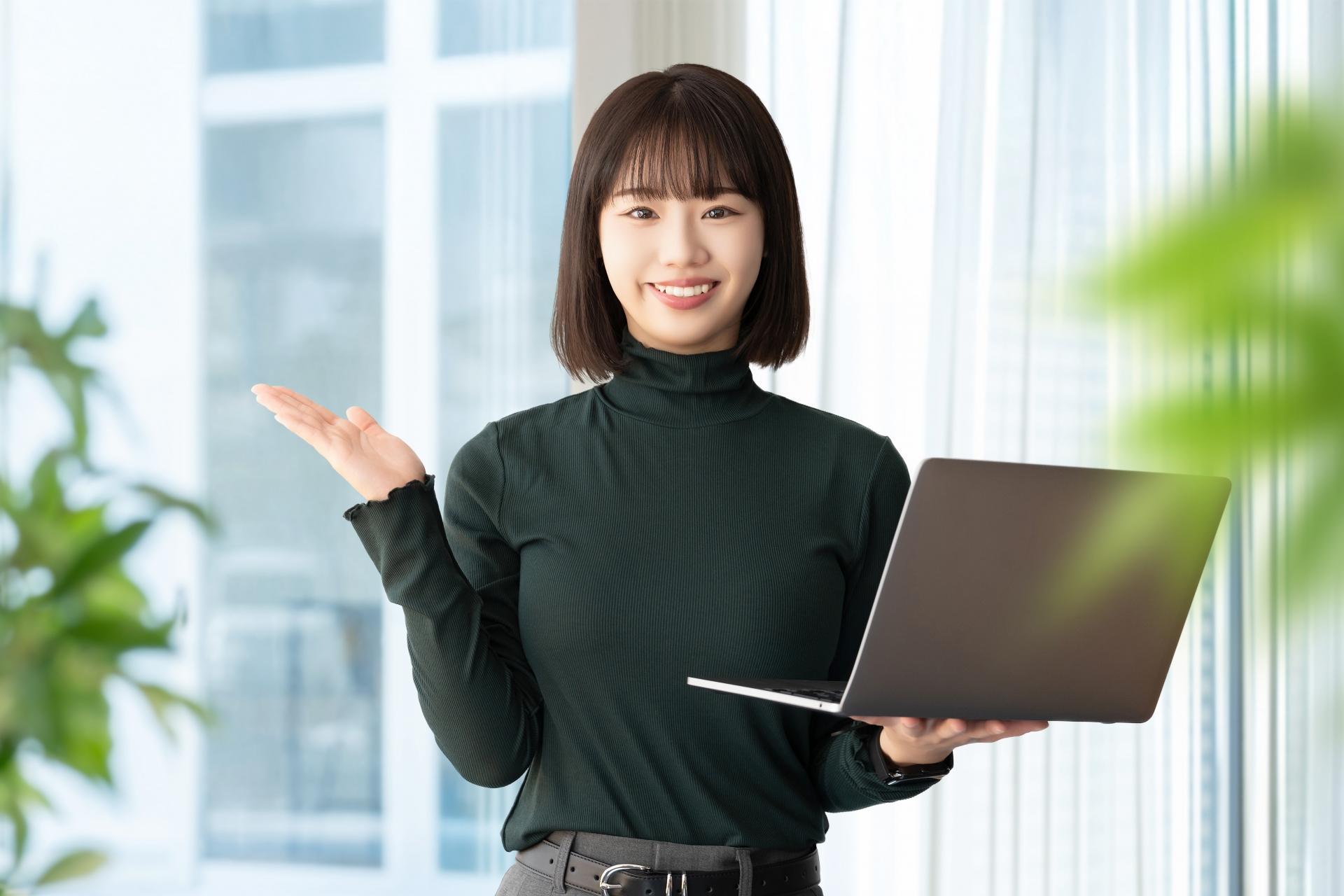 パソコンを持って案内をする笑顔の女性