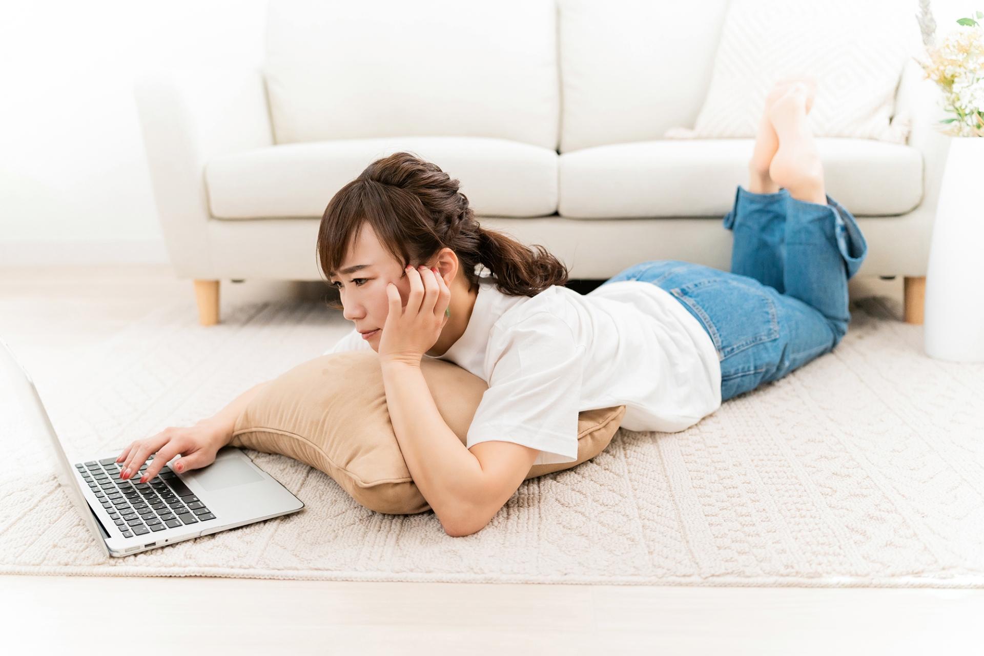 家でパソコンを使いながら困るアジア人女性