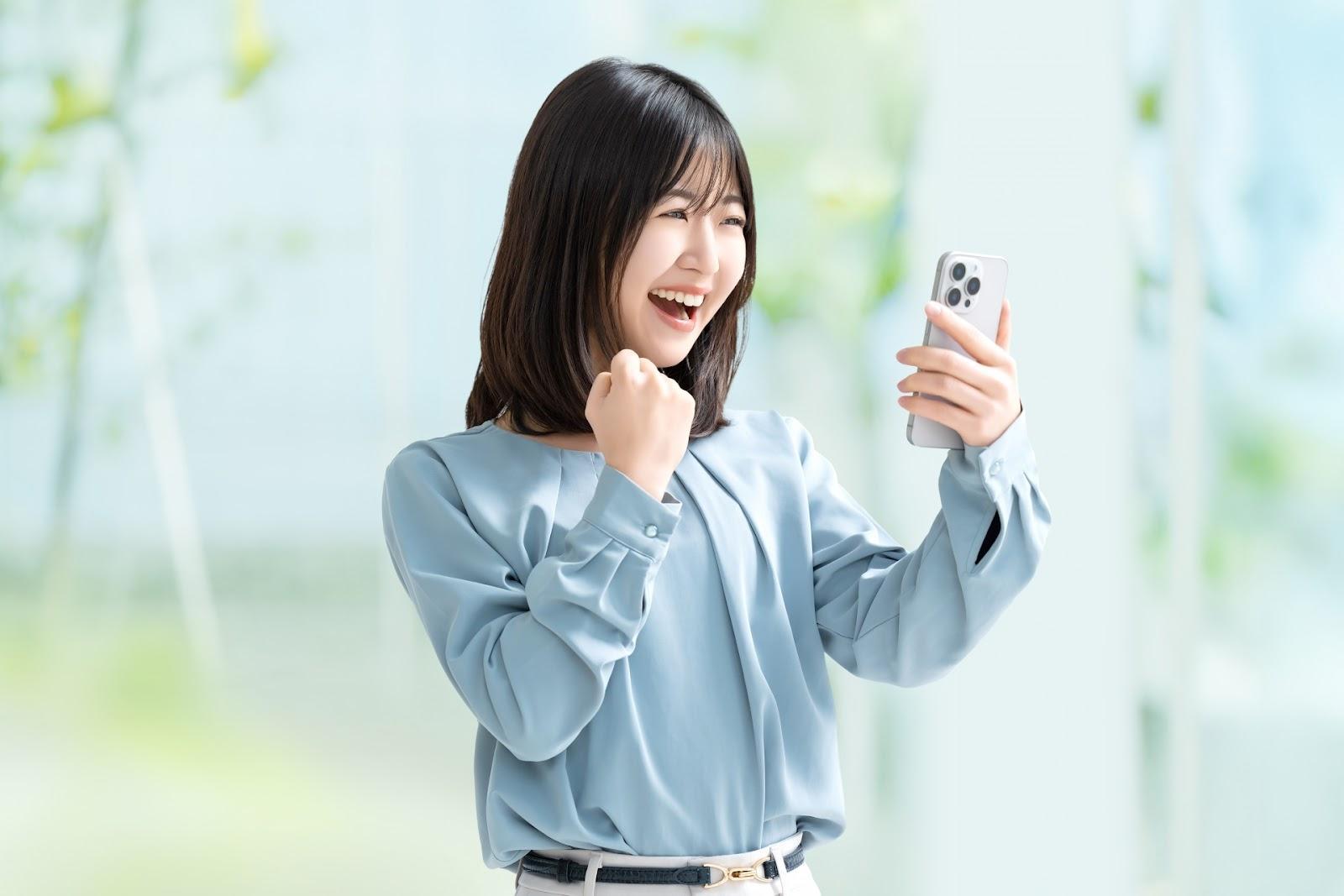 スマホを見て喜ぶ女性・ビジネスウーマン