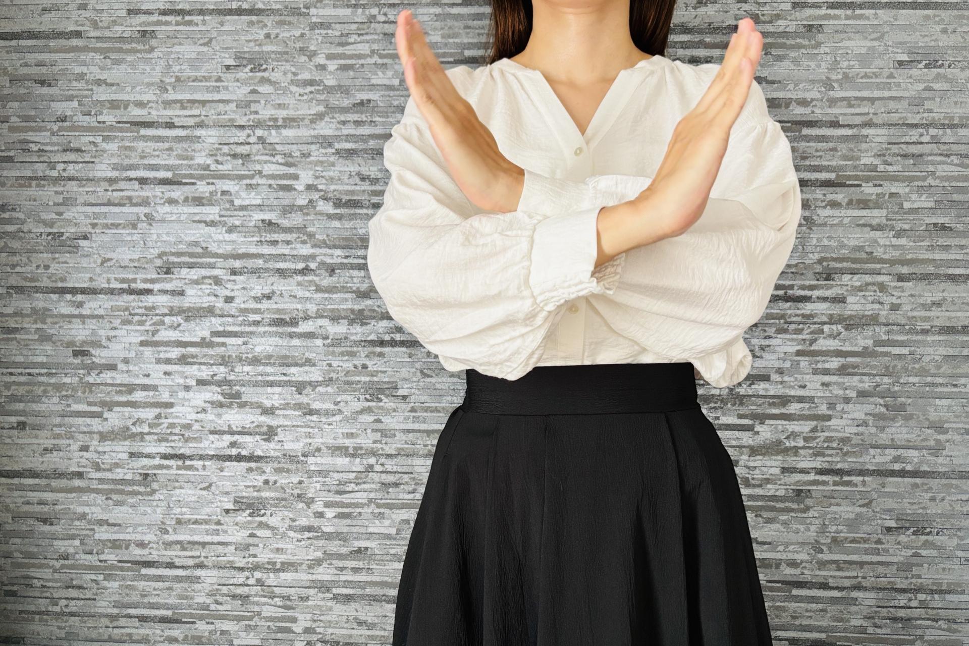 手でバツマークをする女性