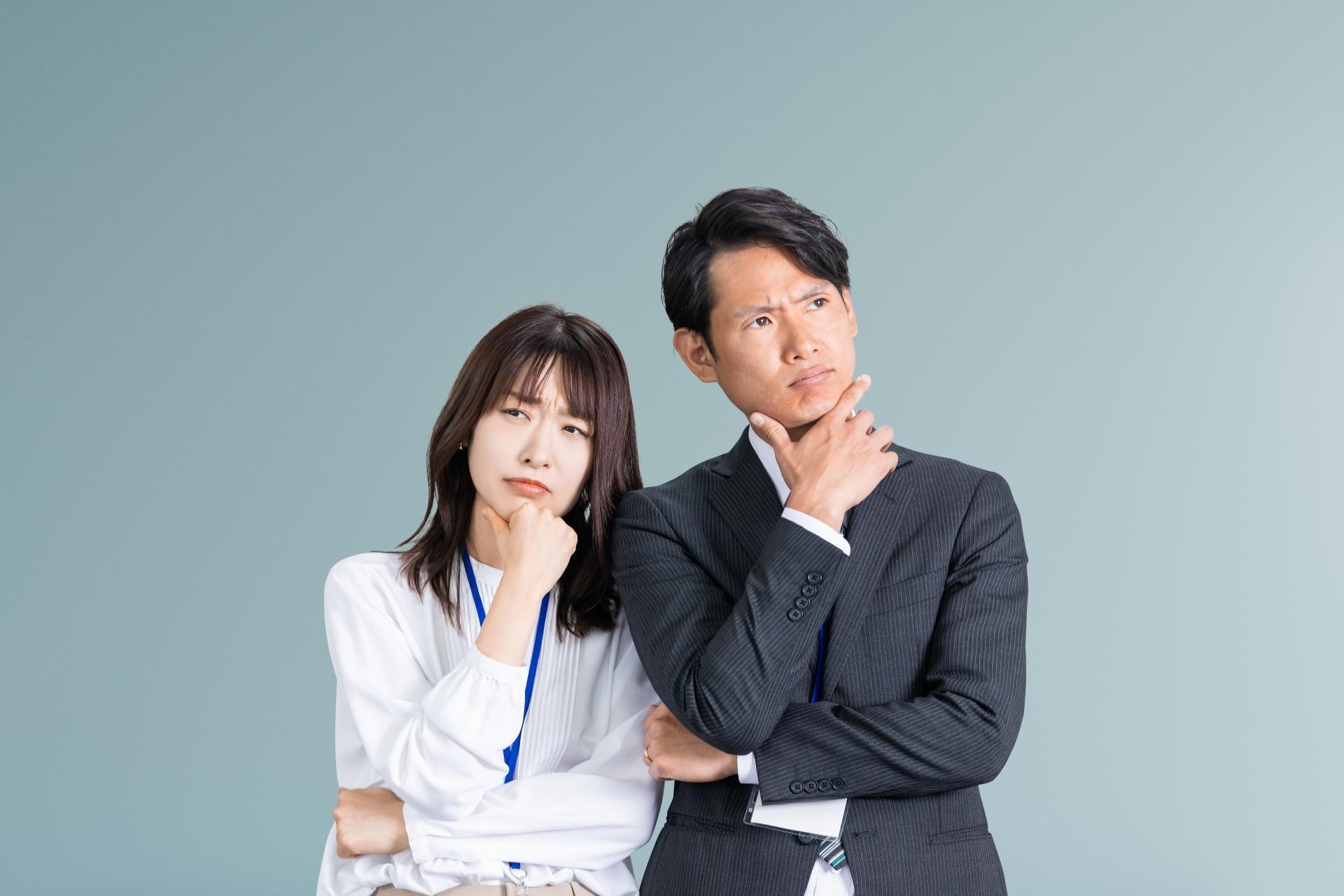 困った顔で考えるビジネスマン男女