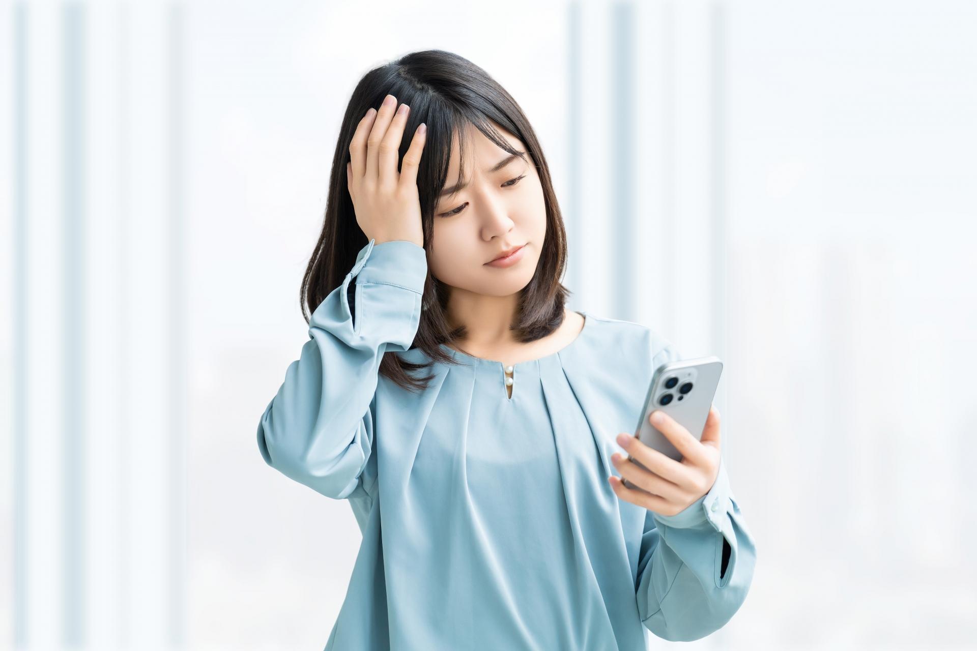 スマホを見て考える女性・ビジネスウーマン